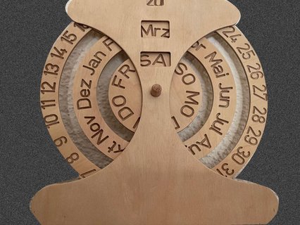 Ewiger Kalender aus präzise gelasertem Flugzeugsperrholz mit drei drehbaren Holzscheiben für Datum, Monat und Wochentag. Die Beschriftung der Ringe ist mit einem feinen Gravierstichel eingraviert und sorgt für klare, langlebige Markierungen. Das Objekt verbindet funktionales Design mit sorgfältiger Holzhandwerkskunst.